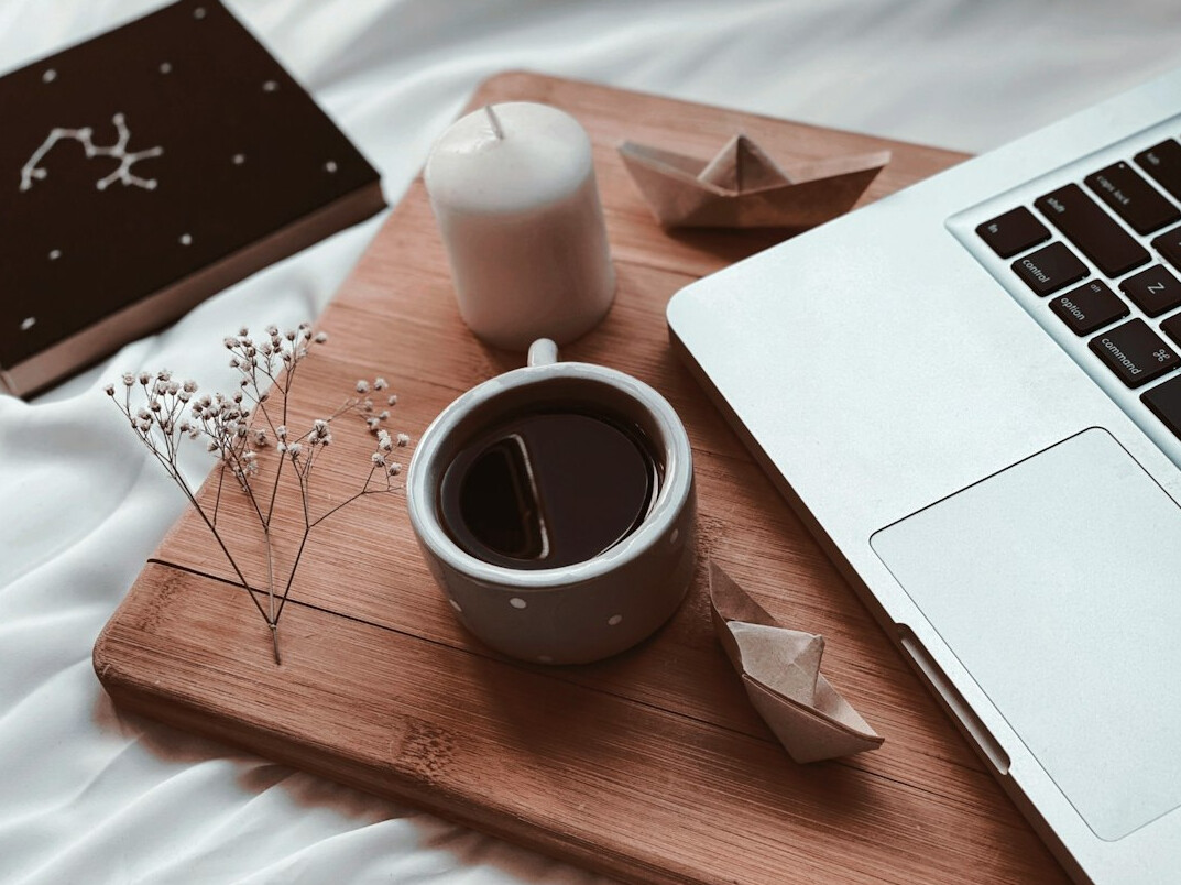 Overhead view of a tidy desk with a laptop, notebook and coffee cup